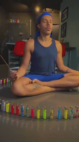 Creator meditando de pernas cruzadas cercado por um círculo de isqueiros Clipper coloridos
